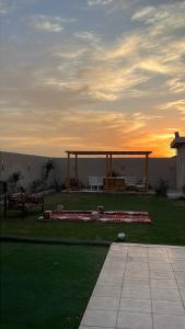 a gazebo in a yard with the sunset in the background at شاليه وردة الدرة in Unayzah