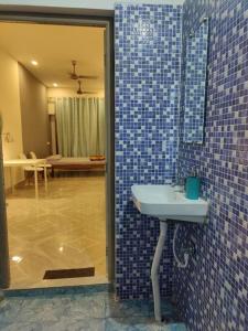 baño con pared de azulejos azules y lavamanos en Minimalistic white stay, en Jorhāt
