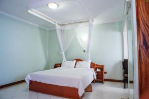 a bedroom with a bed with white sheets and pillows at Jupiter Guest Resort - Langata in Nairobi