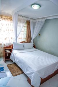 una camera da letto con un letto con lenzuola bianche e una finestra di Jupiter Guest Resort - Langata a Nairobi