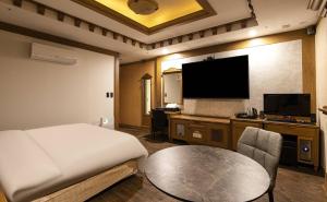Habitación de hotel con cama, mesa y TV. en Doksan 3S Hotel, en Seúl