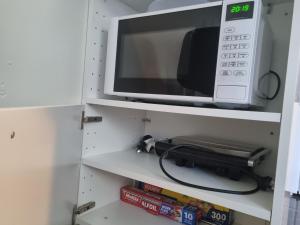 a microwave sitting on top of a shelf at Redcliffe Homestay in Redcliffe