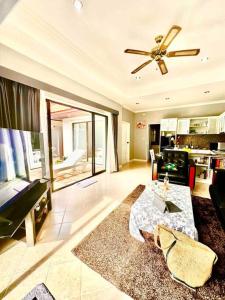 uma sala de estar com uma ventoinha de tecto e uma mesa em Pattaya Jomtien Private Luxury Pool Villa 芭堤雅中天豪华私家泳池别墅 em Praia de Jomtien