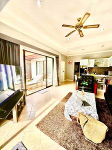 a living room with a ceiling fan and a table at Pattaya Jomtien Private Luxury Pool Villa 芭堤雅中天豪华私家泳池别墅 in Jomtien Beach