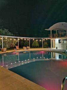 - une piscine la nuit avec des lumières sur une maison dans l'établissement Casa de Campo con Piscina, à Tingo María