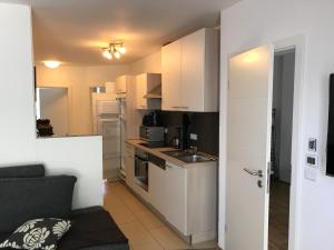 a small kitchen with white cabinets and a couch at zum Dünengras in Saal