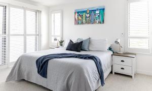 a white bedroom with a bed with a blue blanket on it at Beach House 4 brm, 3 mins walk to beach in Alexandra Headland