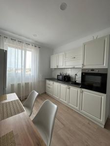 a kitchen with white cabinets and a table and chairs at Fortress Apartament in Oradea