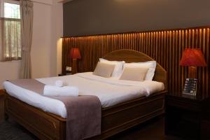 um quarto com uma cama grande e uma cabeceira em madeira em Red Panda Apartment em Darjeeling
