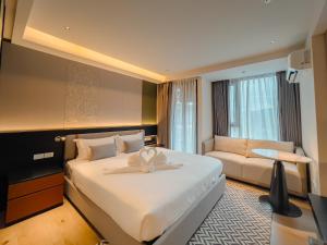 Habitación de hotel con cama grande y sofá en Cha Chiangmai Luxury, en Chiang Mai