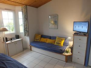 een kamer met een bank met gele kussens en een televisie bij Appartement La Rotonde à Port Bourgenay in Talmont
