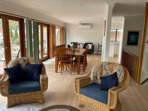 a living room with wicker chairs and a dining room at Wanda House - Close to beach Linen Pets in Salamander Bay