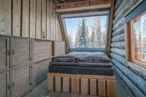 ein Schlafzimmer in einem Blockhaus mit einem Bett und einem Fenster in der Unterkunft Lapland Lodge in Tepsa