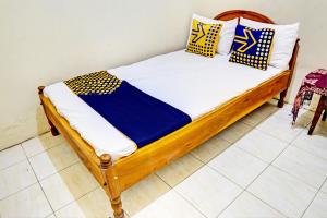 ein Holzbett mit blauen und gelben Kissen darauf in der Unterkunft OYO 93108 Homestay H Syarif Syariah – RA Kartini in Gresik