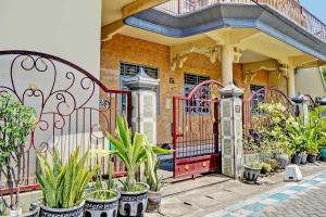 um portão vermelho em frente a uma casa com vasos de plantas em OYO 93108 Homestay H Syarif Syariah – RA Kartini em Gresik