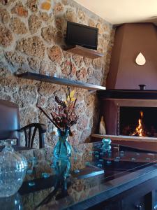 a living room with a stone wall with a fireplace at Ξενώνας Λίκνο in Synikia Mesi Trikalon