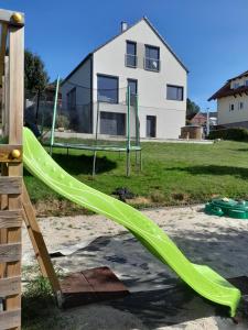 un tobogán verde en un parque infantil frente a una casa en Lipnohaus en Horní Planá
