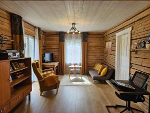 uma sala de estar com paredes de madeira e uma mesa e cadeiras em Metsavahi puhketalu 