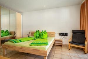 a bedroom with a bed with green sheets and a chair at Ferienwohnung Buchmann in Deggenhausertal
