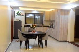 a kitchen with a table with chairs and a refrigerator at Bright cozy APT in the heart of Naguru in Kampala