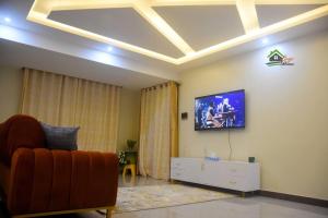 a living room with a couch and a tv on the wall at Bright cozy APT in the heart of Naguru in Kampala