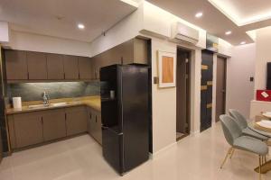 a kitchen with a black refrigerator and a sink at Stylish 2 Bedroom Condo Near BGC and Airport with Fast WiFi in Manila