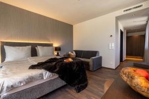 a bedroom with a large bed and a couch at Hotel Finkenhof - Feel at home in Schenna