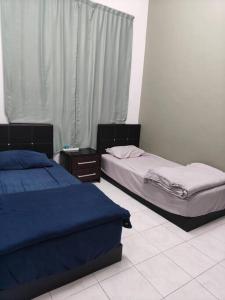 een slaapkamer met 2 bedden en een raam bij June's Homestay@ Puteri Wangsa near Aeon & IKEA in Ulu Tiram