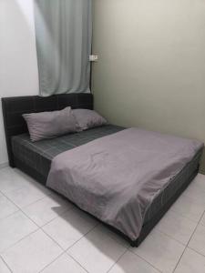 a bed with a black frame in a room at June's Homestay@ Puteri Wangsa near Aeon & IKEA in Ulu Tiram