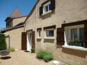 une maison avec 2 fenêtres et des fleurs dans une cour dans l'établissement Les Sureaux Le Gite 3 étoiles par CDT24, à Le Pizou