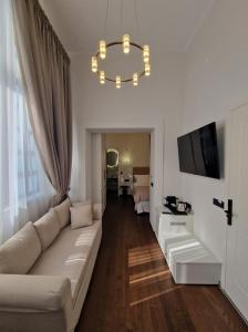 a white living room with a couch and a television at Jensen Luxury Suites in Rhodes Town
