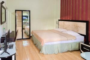 a bedroom with a bed and a desk and a television at Global Inn Syariah Mitra RedDoorz near Juanda T1 Airport 