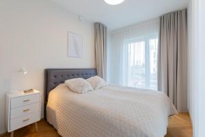 a white bedroom with a bed and a window at Cozy Stay Apartment in Pärnu
