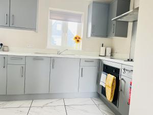 cocina con armarios blancos, fregadero y ventana en Brand New 1 Bed Apartment, 5min Walk to Racing & Main Strip, with Electric Parking Bay & Terrace LONG STAY WORK CONTRACTOR LEISURE - CITRINE en Newmarket