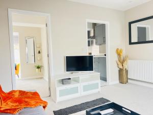 a living room with a tv on a white wall at Brand New 1 Bed with Sofabed, Private Patio & Electric Parking Bay, 5min Walk to Racing & Main Strip LONG STAY WORK CONTRACTOR LEISURE - AMBER in Newmarket