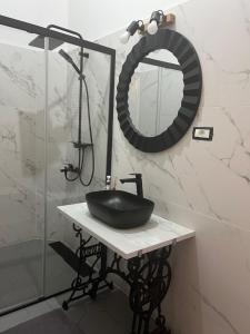 ein Bad mit einem schwarzen Waschbecken und einem Spiegel in der Unterkunft Barty downtown apart 2 in Timişoara