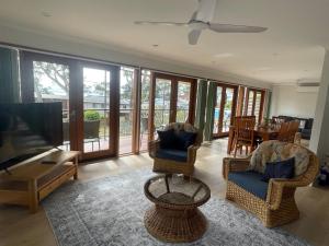 a living room with chairs and a flat screen tv at Wanda House - Close to beach Linen Pets in Salamander Bay