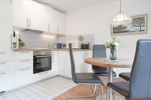 cocina con armarios blancos, mesa y sillas en Harringsredder Harringskoje, en Malente