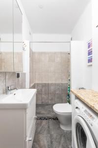 a bathroom with a toilet and a sink and a washing machine at Elektoralna 19 by Homeprime in Warsaw