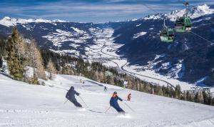 two people skiing down a snow covered slope with a ski lift at Am Waldrand 252 in Neukirchen am Großvenediger