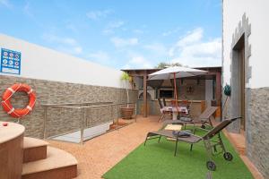eine Terrasse mit Stühlen, einem Sonnenschirm und einem Tisch in der Unterkunft Casa Barriguita in Yaiza