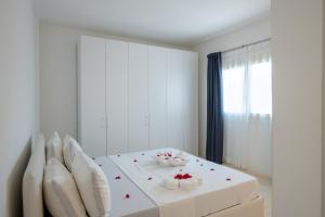 a white room with a bed with red flowers on it at Ocean View Penthouse with Jacuzzi Elias Homes ZanzibarHouses in Gulioni