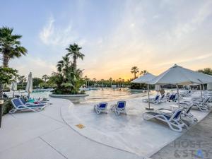 - une piscine avec des chaises longues et des parasols dans un complexe dans l'établissement Studio in Golf Vista, Damac Hills - Host & Stay, à Dubaï