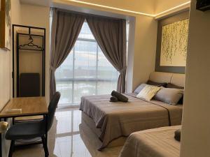 a bedroom with two beds and a desk and a window at Home Sweet Home 2 rooms Apartment in Melaka