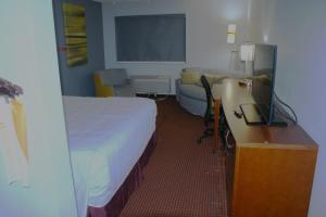 a hotel room with a bed and a desk with a television at Van Buren Inn in Van Buren