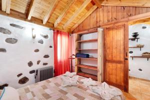 - une chambre avec un lit et un mur en bois dans l'établissement Casa Rural Medina 2, à San Sebastián de la Gomera