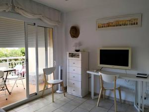sala de estar con escritorio, TV y sillas en Apartamento con piscina junto a la playa, en Sant Antoni de Calonge