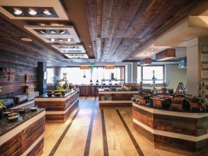 un ristorante con pavimenti in legno e una cucina con ripiani di Falkensteiner Family Hotel Sonnenalpe a Sonnenalpe Nassfeld
