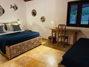 a bedroom with a bed and a desk and a chair at The Barra Grande Guesthouse & Hostel in Barra Grande