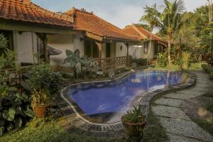 a swimming pool in front of a house at Villa Chempaka in Ubud